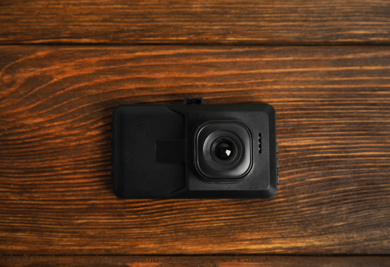 Modern Car Dashboard Camera on Wooden Background, Top View